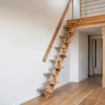 Escalier à pas japonais en bois clair avec marches décalées installé dans un petit espace et menant à une mezzanine.