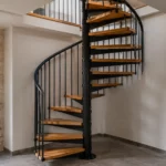 Escalier en colimaçon : la méthode complète, du choix des fixations à la pose Escalier en colimaçon entièrement installé dans une maison avec colonne centrale métallique, marches en bois massif, garde-corps et main courante incurvée.